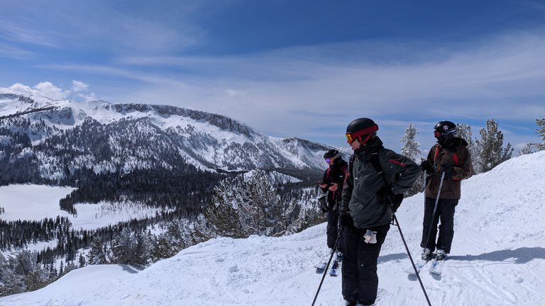 Two people on a snowy hillside look sideways toward the camera.