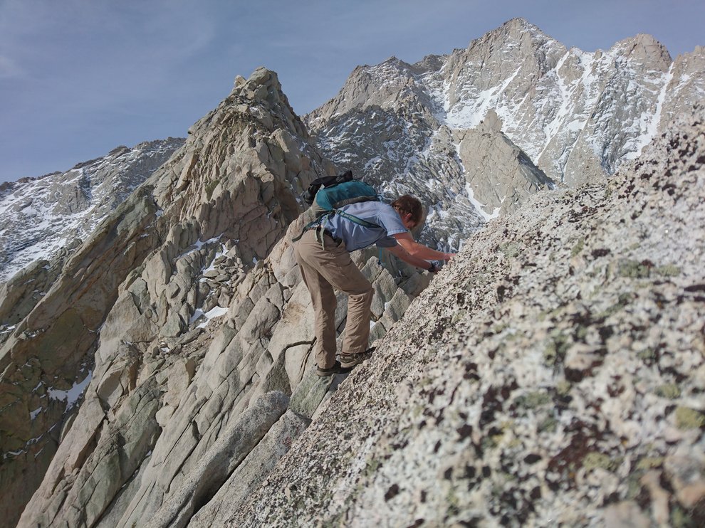 Dusting climbing a rocky steep slope. Mountain ridges in the background, slightly snow-covered.