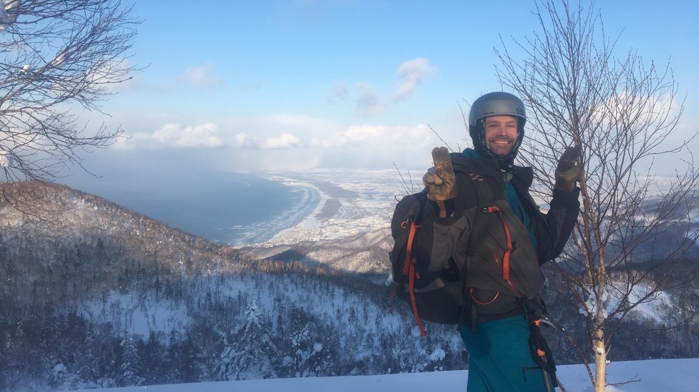 Ben in full gear in the background, view of the mountains and the ocean in the background.