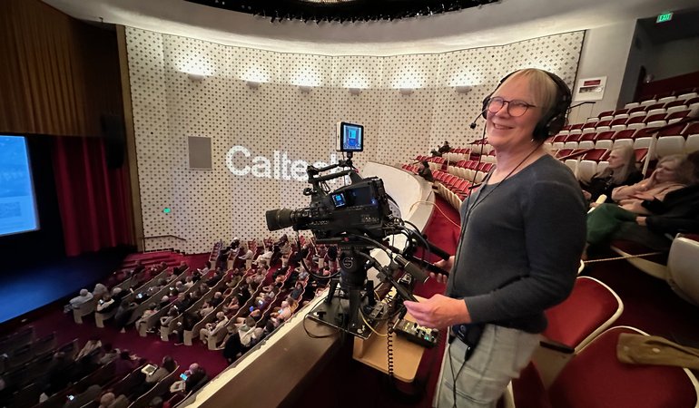 camera operator working in Beckman balcony smiling at camera