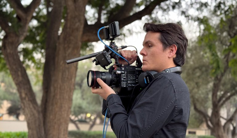 male operating camera with tree in background