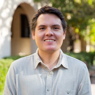Man with grey button up shirt smiles at camera