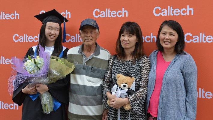 graduate and family posing in front of a Caltech display