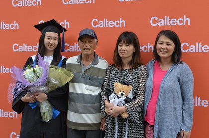 graduate and family posing in front of a Caltech display