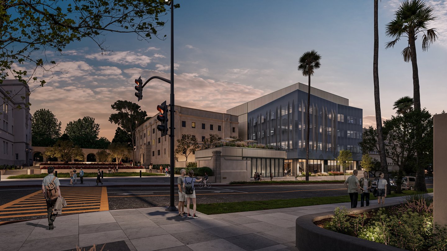 glass building with palm trees. sky is dark blue and ornage at sunset.
