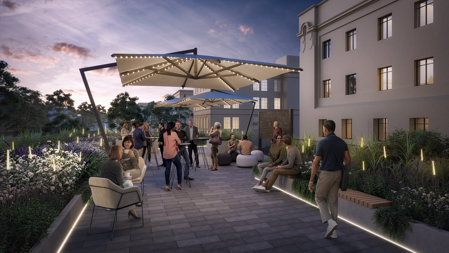 patio with umbrellas, people, and plants and flowers. Buildings are in the background.