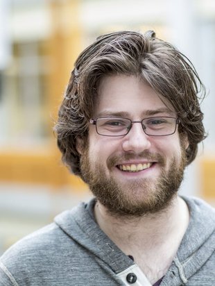 Person with short hair smiling with a glasses on