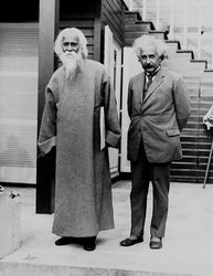 Bengali poet Rabindranath Tagore to Einstein's right, standing on the back patio of Einstein's summer home. Tagore in customary clothes, a long sleeved robe like garment. Einstein in a suit and tie, holding his pipe, squinting at the camera.