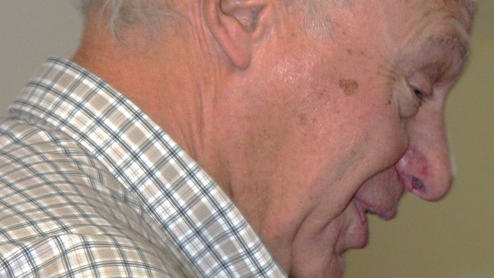Profile of John Stachel, wearing light plaid collared shirt, looking downward. Photo taken 2002.