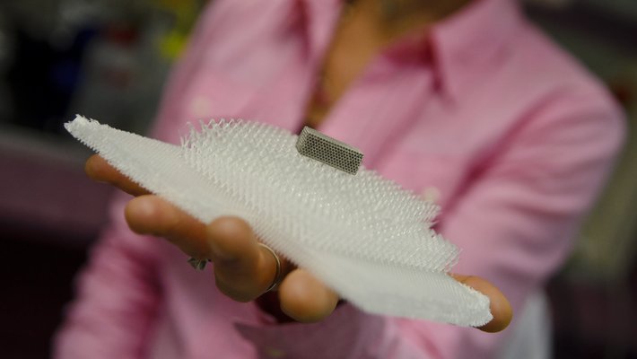 Julia Greer holds microtruss structure in the palm of her hand.