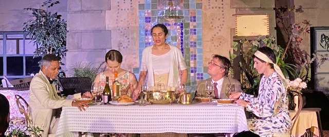 The actors gather around the table.
