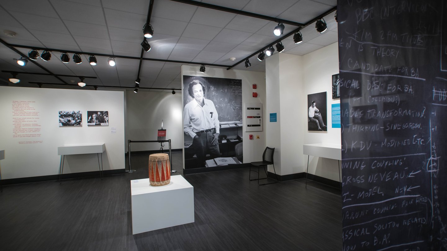 art exhibit including drum and large photo of Richard Feynman leaning against a blackboard