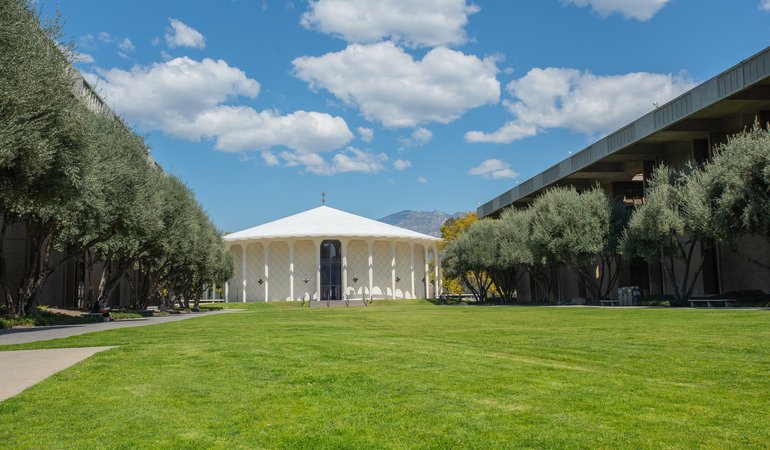 A large lawn with a white, round building in the background