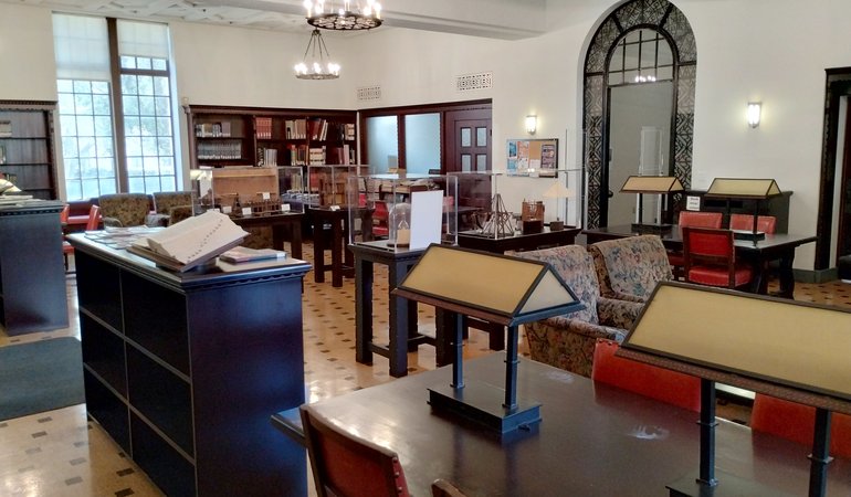 A library with tables topped with reading lamps and cushioned chairs for more relaxed reading.