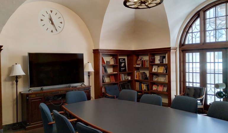 A small reading room with a center table and shelves of books against the walls.