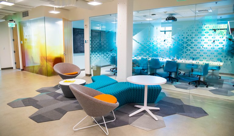 A futuristic and colorful lounge area features a geometric motif and includes chairs and a small table.