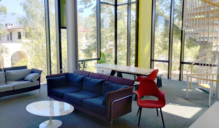 A lounge area with large glass windows and trees outside