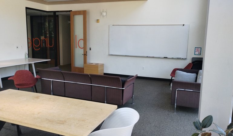 A study area with a couch, chairs, and whiteboard