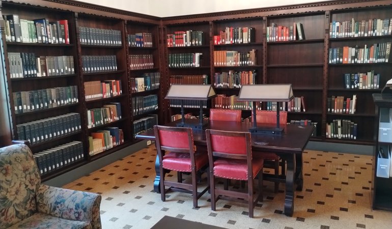 A library with tables topped with reading lamps and cushioned chairs for more relaxed reading.
