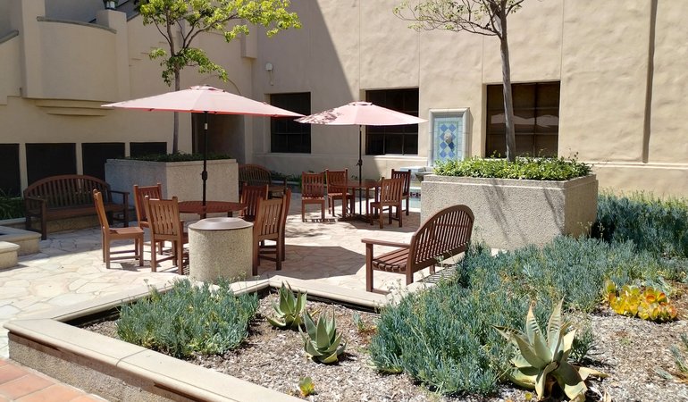 An outdoor patio area with tables, chairs, umbrellas, and planters