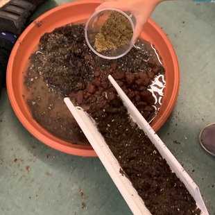 A miniature flume experiment to measure soil and water flow, with a hand pouring a cup of sand.