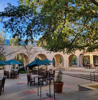 view of Avery Exterior Courtyard and Patio with picnic tables and umbrellas, planters, and the breezeway separating the courtyard from the main sidewalk