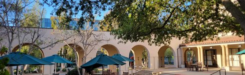 view of Avery Exterior Courtyard and Patio with picnic tables and umbrellas, planters, and the breezeway separating the courtyard from the main sidewalk