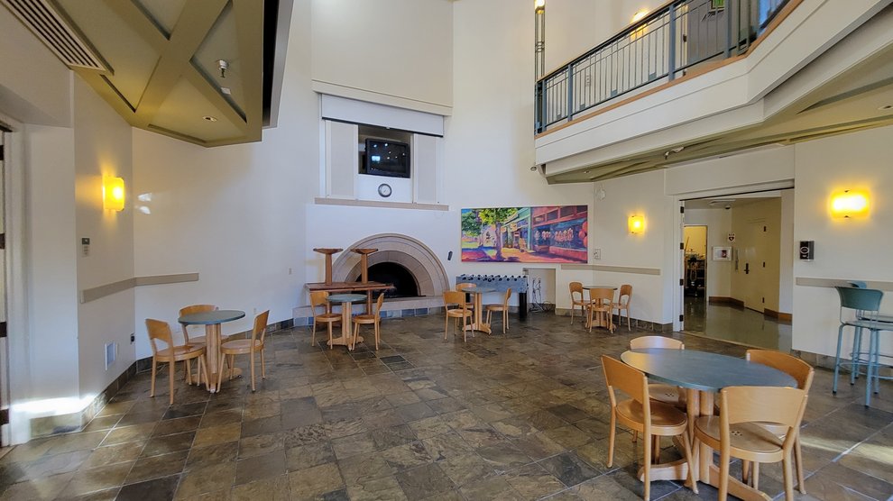 interior view of Avery Dining Hall with tables and chairs, a large fireplace, art on the wall, and a second floor dining space overlooking the room