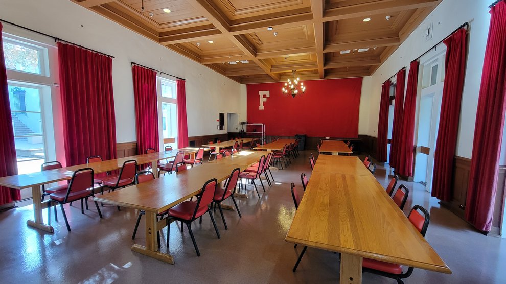 view inside Fleming House Dining Hall with long dining tables stretching the length of the room and red walls donning the Fleming "F" in white