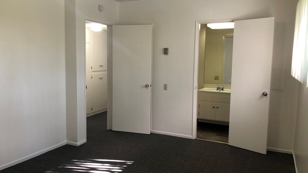 Empty bedroom with view of bathroom and hallway.