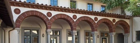 Exterior of a house with arches and columns. Brick flooring in the courtyard.