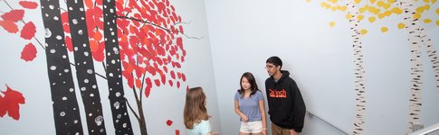 Students talking near murals of trees at Lloyd House