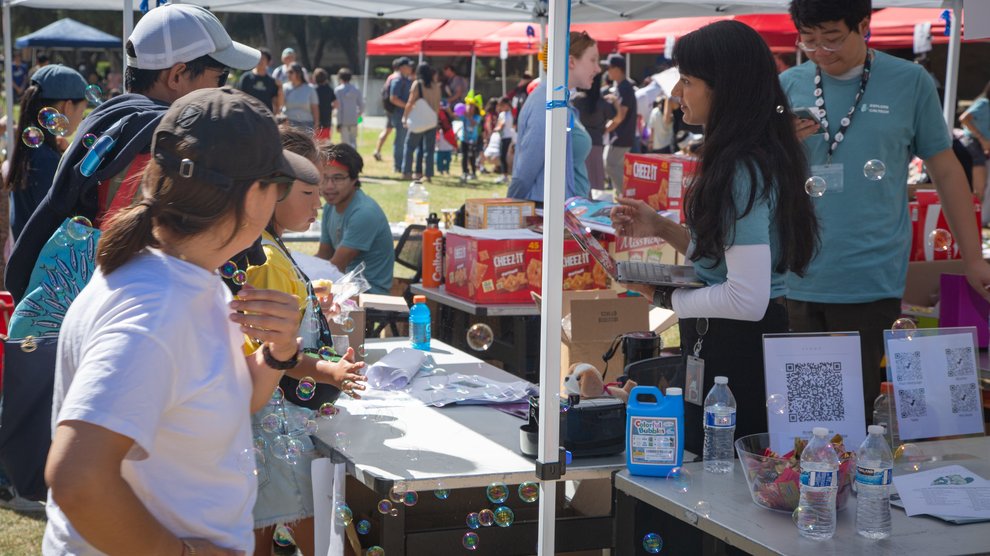 Bubbles floating around participants and volunteers at an interactive science booth