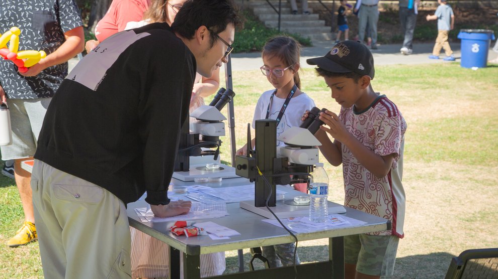 A volunteer guides a child through using a microscope