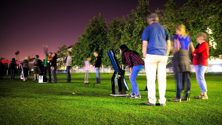 People gathered around telescopes under night sky