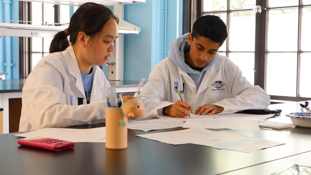 Two students writing at a desk