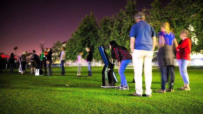 People gathering around telescopes at night