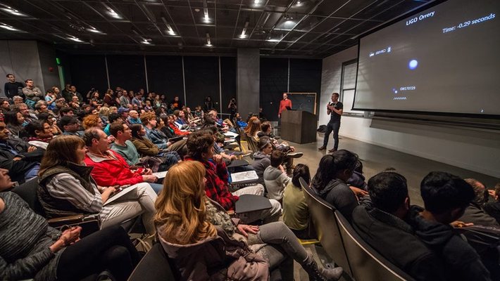 A lecture hall with a student audience listening to a science presenter