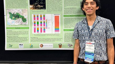 Isaac smiling in front of research poster