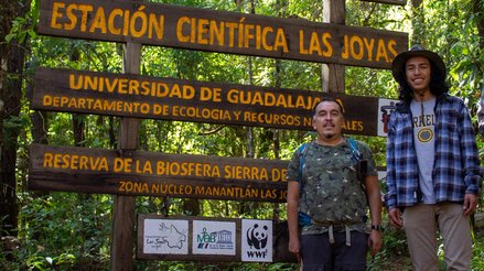 Isaac and a partner smiling in front of the entrance to the Sierra de Manantlan Biosphere Reserve
