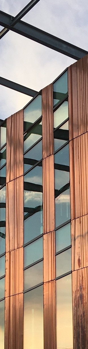 Close up image of the exterior glass and copper facade of the Chen Neuroscience Research Building at dusk.