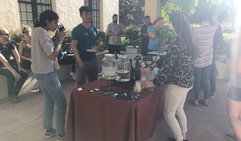CWiN members, graduate students and postdocs, socializing on an outside patio by a table of food and drinks.