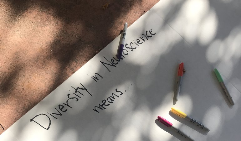 White poster board with the text "Diversity in Neuroscience means..." and colored pens.