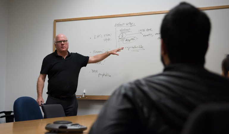 Photograph of Colin Camerer teaching students at a white board