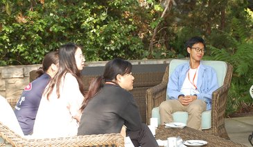 DataSAI Summer School Students sitting on wicker furniture on a garden patio