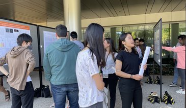 Students looking at posters on poster boards outside