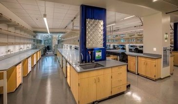 Lab space with grey counter tops, open upper shelving and light wood lower cabinets.
