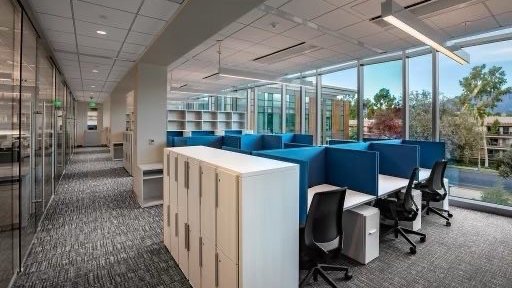 Lab write up area with tables, blue dividers, lockers and large glass floor to ceiling windows.