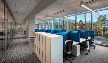 Lab write up area with tables, blue dividers, lockers and large glass floor to ceiling windows.