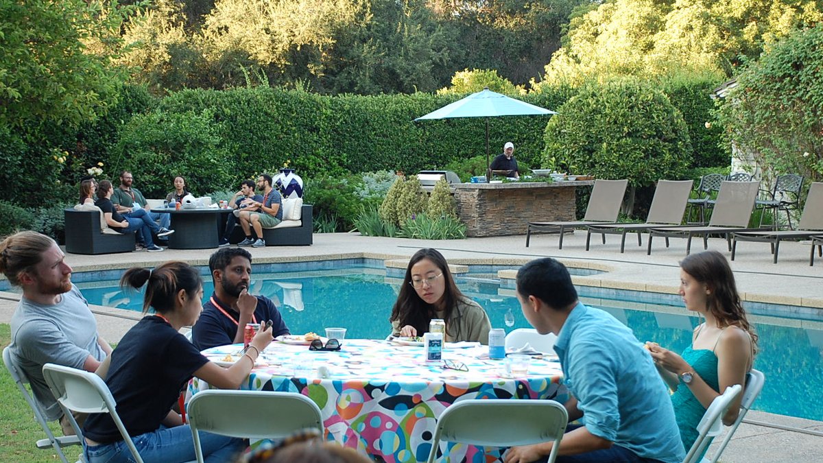 DataSAI Summer School Students sitting at a table next to a pool